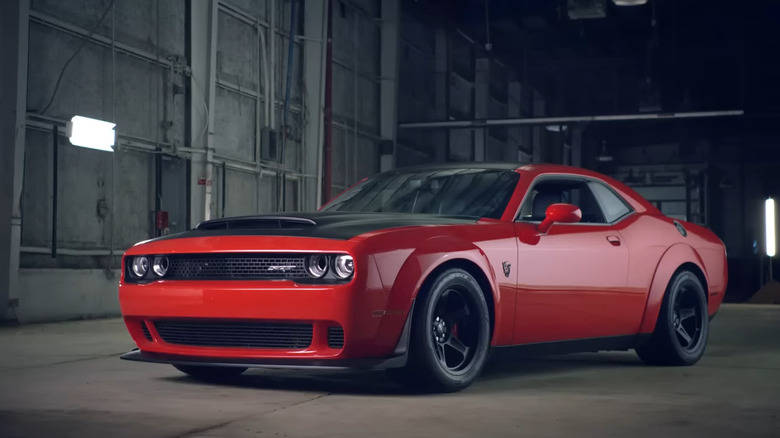 A red Dodge Demon sits parked menacingly in an industrial garage.