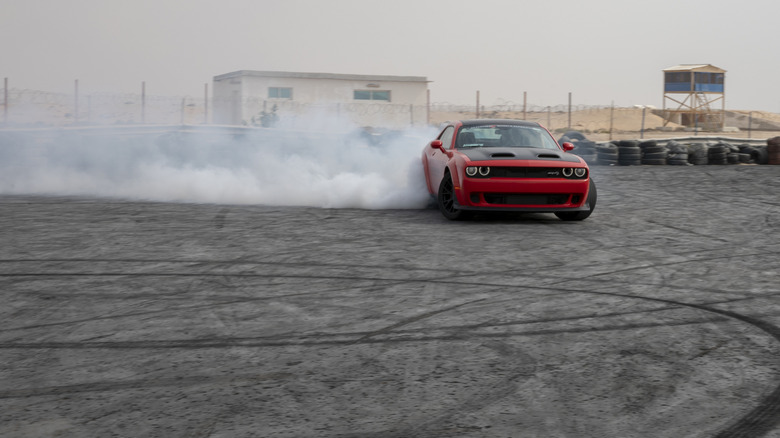 A Challenger Hellcat slides sideways as the rear tires smoke.