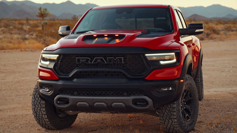 A red pickup faces the camera with desert mountains in the background.