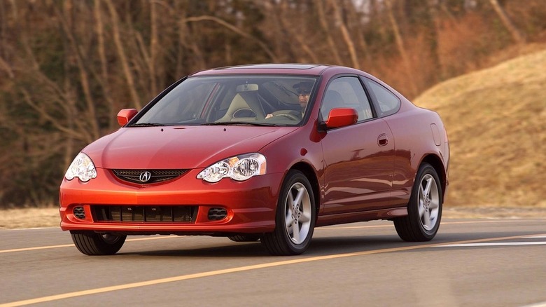 A metallic red 2002 Acura RSX Type-S driving along a two-lane asphalt road.