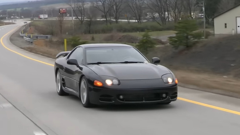 A black Mitsubishi 3000GT sports coupe driving down a road.
