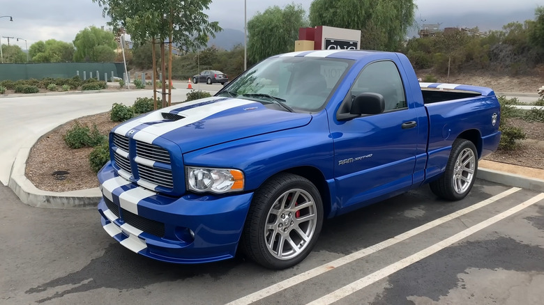 A blue Dodge Ram SRT-10 pickup truck with white racing stripes sits in a parking lot.