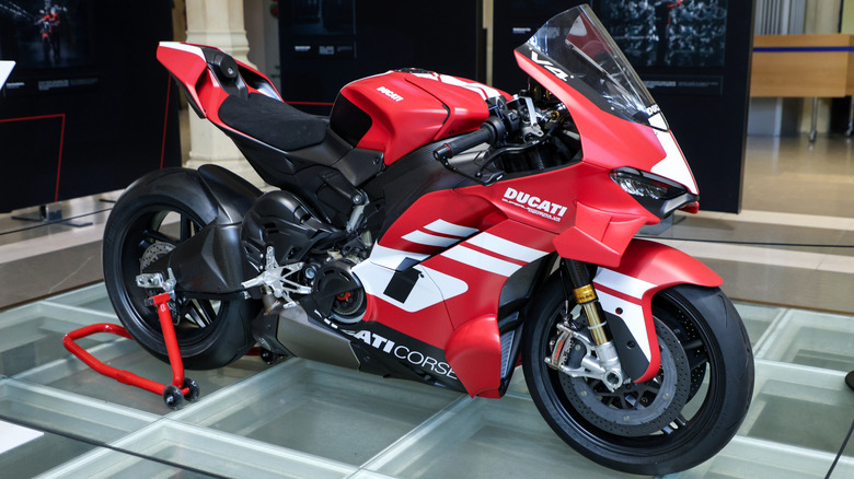 A red-and-white Ducati Superleggera V4 Centenario parked on a show stand.