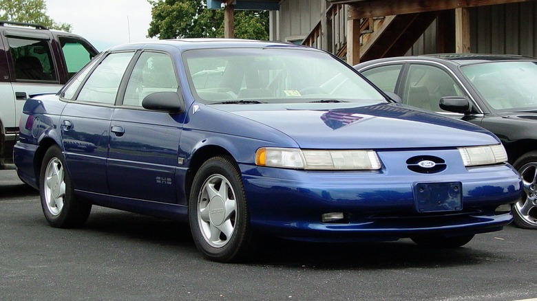 A blue Ford Taurus SHO sits parked.