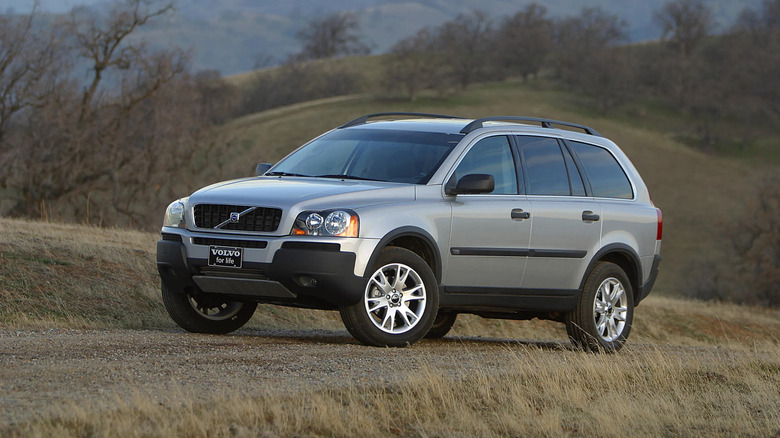 A silver Volvo XC90 parks on a dirt road.