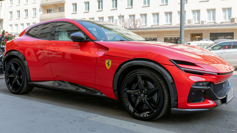 A red Ferrari Purosangue parked by the side of a road.