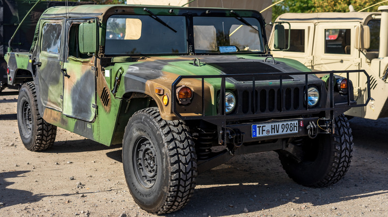 A camo-coloured Humvee Model 998 parked on a dirt surface.