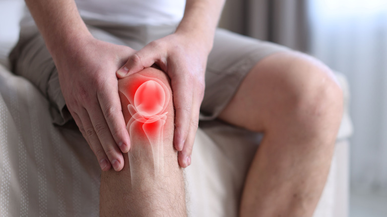 Man rubbing sore knee with image of joint overlayed