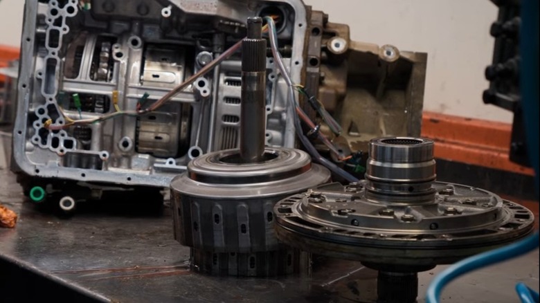 The insides of an Aisin AS69RC transmission spread on a workbench.