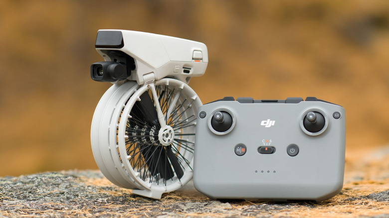 A DHI Flip folded-up next to controller and sitting on a rock