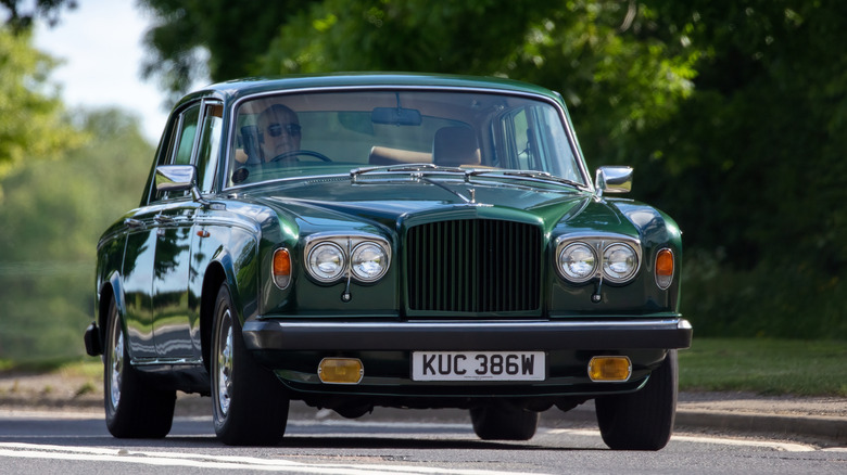 A dark green Bentley T2 driving down a country lane