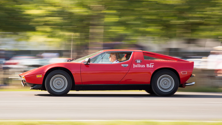 A dynamic side shot of a red Maserati Merak SS driving fast on the road