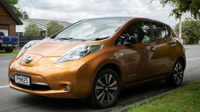 An early Nissan Leaf parks outside.