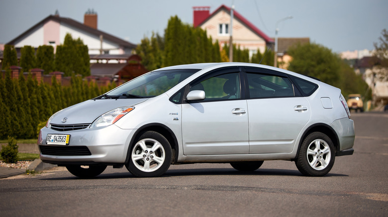 An older Prius parks in a neighborhood.
