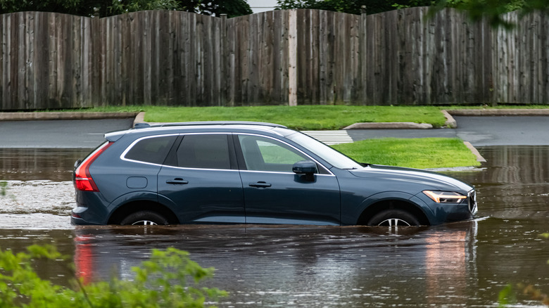 A flood damaged vehicle sits in deep water.