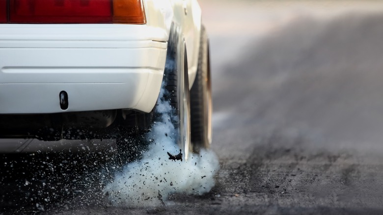 Car peels out, kicking up dust and asphalt.