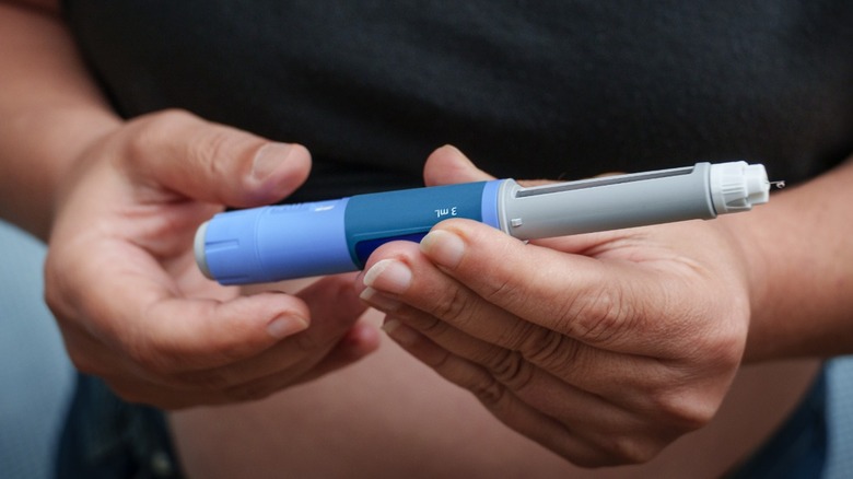 Closeup of a person's hands holding an insulin pen.