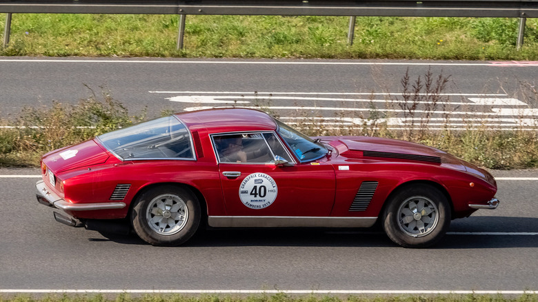 A side shot of a red 1972 Iso Grifo sporting the number 40 driving on the highway