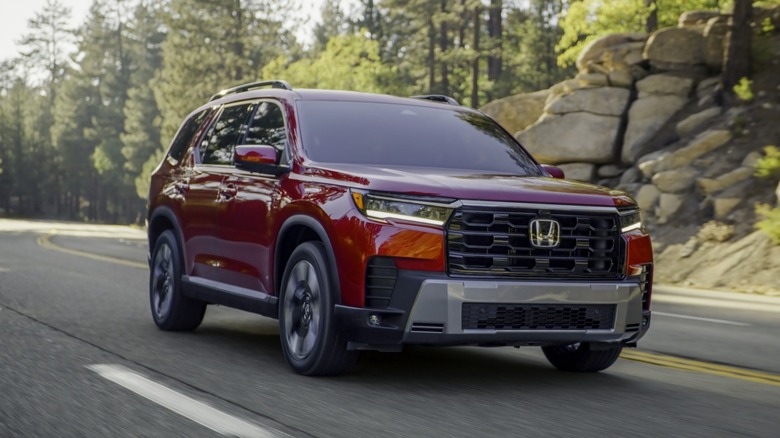 A front 3/4 view of a red 2026 Honda Pilot in motion.
