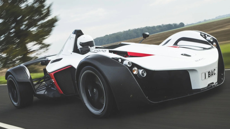 A dynamic driving shot of a white BAC Mono with red and black accents