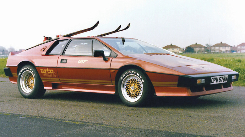 A red 1980s Lotus Esprit Turbo with skis on top, Goodyear tires, and a James Bond-style "007" on the door