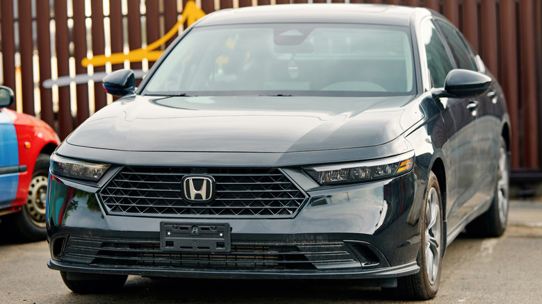 A black Honda Accord parked in front of a brown fence.