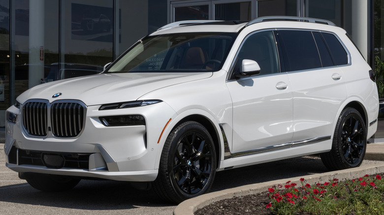 A white BMW X7 parked in front of a dealership.