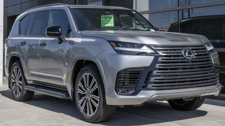 A silver Lexus LX 700h parked outside a dealership.