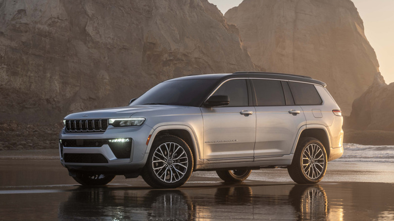 A silver 2026 Jeep Grand Cherokee L in on a beach in front of rocks