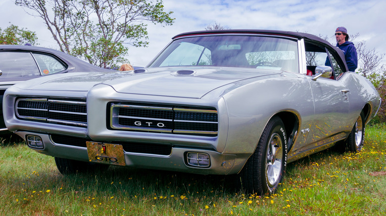 A rare gray 1969 Pontiac GTO without Judge decals, parked on the grass at a car show.