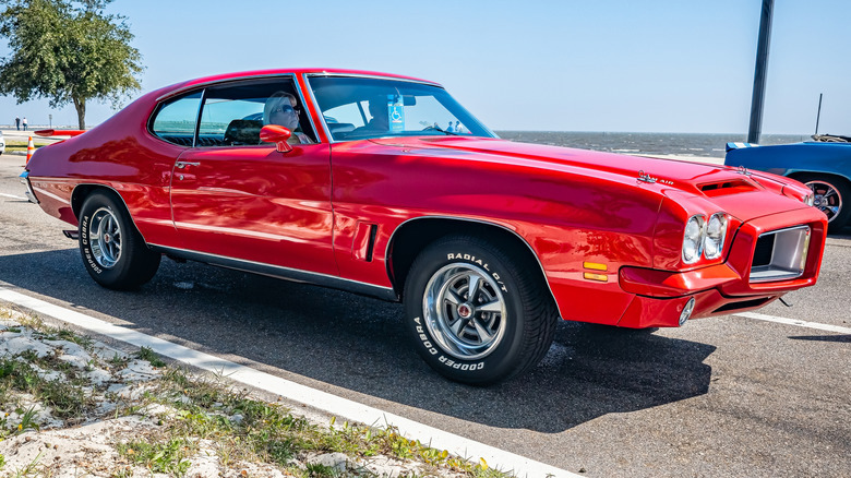 A red 1972 Pontiac GTO Hardtop Coupe parked by the ocean.