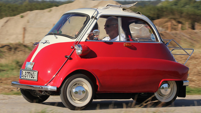 A red and cream BMW Isetta microcar driving along the road