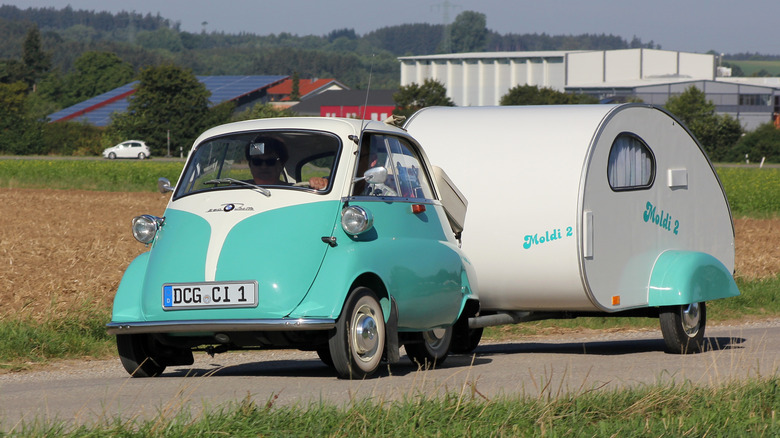 A teal and cream BMW Isetta pulling a similarly colored camper