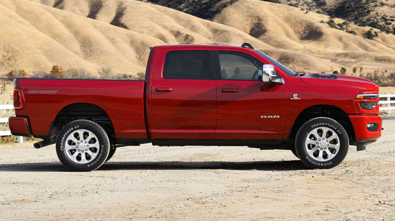 A red Ram HD truck in profile parked at the base of a mountain