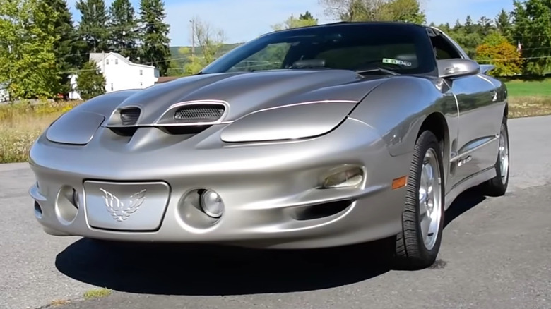 A pewter metallic Pontiac Firebird Trans Am WS6 with functional Ram Air hood scoops on an open road.