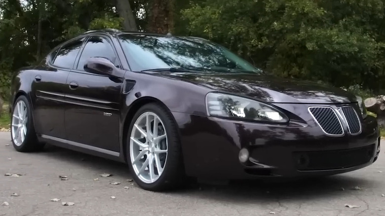 A dark purple 2005–2008 Pontiac Grand Prix GXP sedan with silver multi-spoke wheels on an asphalt road.
