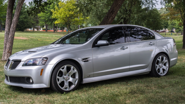 A silver Pontiac G8 sedan with tinted windows parked on a grassy lawn.