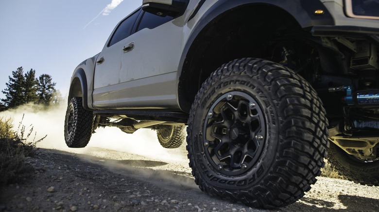 A Ford F-150 Raptor airborne on a dirt trail, highlighting a front BFGoodrich Mud-Terrain T/A KM3 tire.