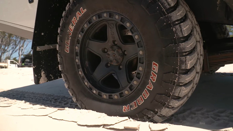 General Tire Grabber X3 mud-terrain tire mounted on a dark multi-spoke wheel on a white truck.