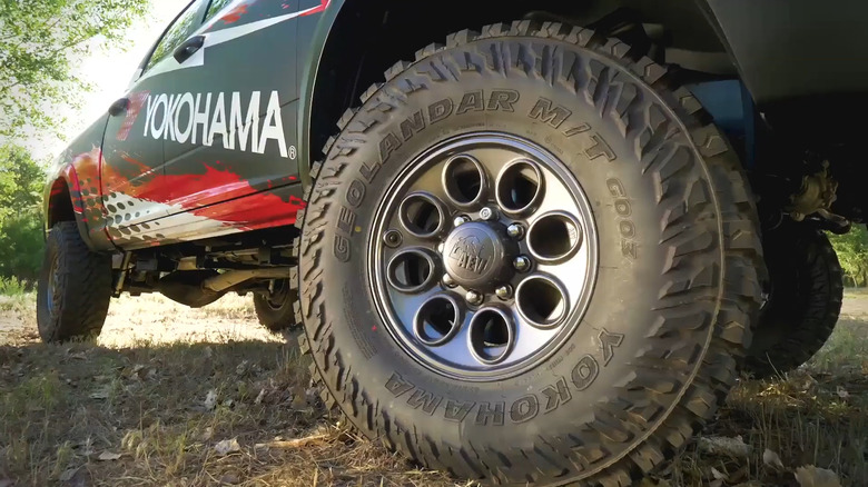 A Yokohama Geolandar M/T G003 tire mounted on a dark AEV wheel on a branded Ram trail truck.