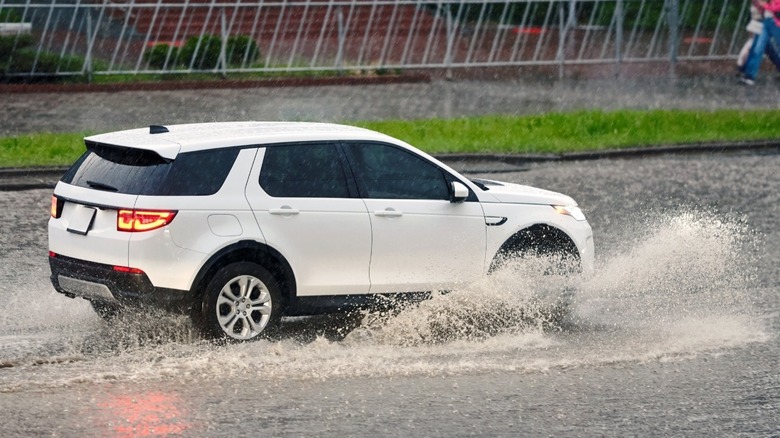 A white SUV drives through deep water