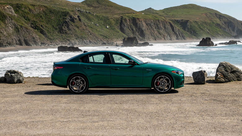 A green 2026 Alfa Romeo Giulia near a beach with cliffs and crashing waves in the distance