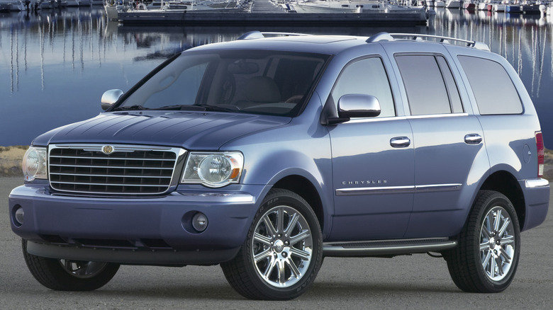 A blue 2007 Chrysler Aspen SUV parked in front of a boat-filled marina.