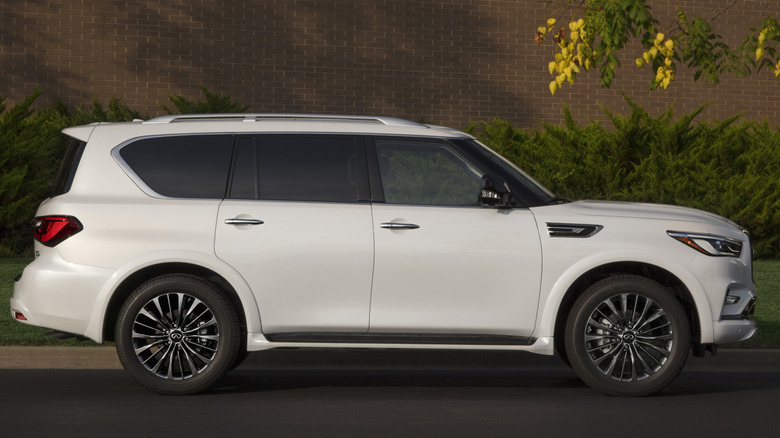A white 2021 Infiniti QX80 in front of a brick building.