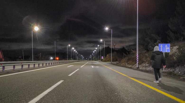 A man walking along highway at night