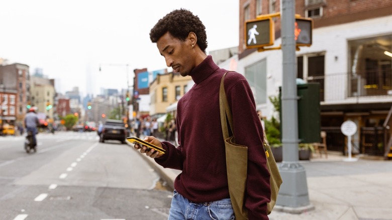 A man crossing street while looking at a smartphone
