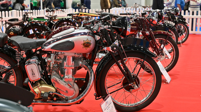 Vintage motorcycles on display on a red carpet.
