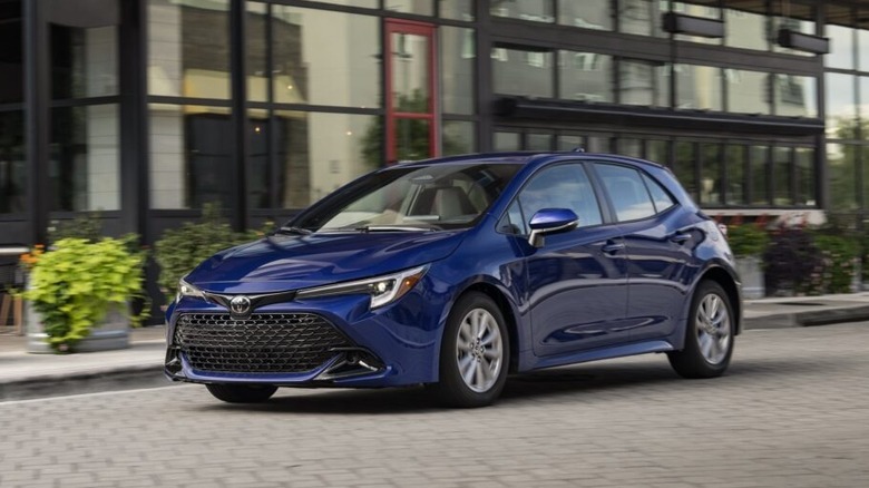 A 2021 Toyota Corolla Hatchback on paver stones in front of a glass-fronted building.