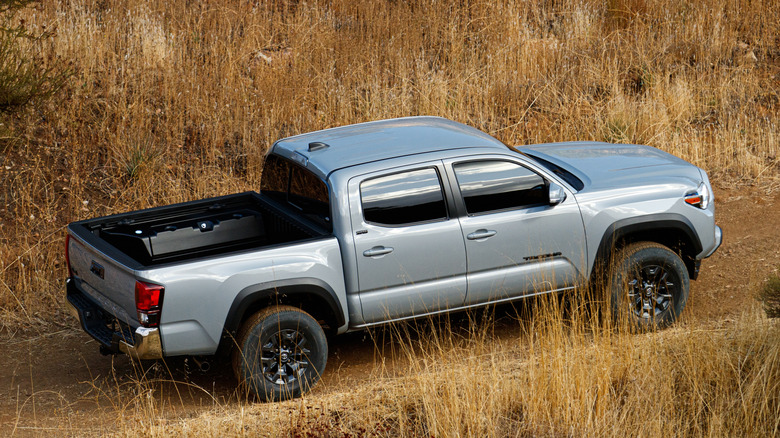 A gray 2021 Toyota Tacoma on an unpaved trail in front of a hill.