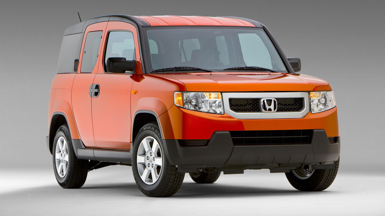 An orange 2011 Honda Element SUV seen in right front three-quarter view in a studio